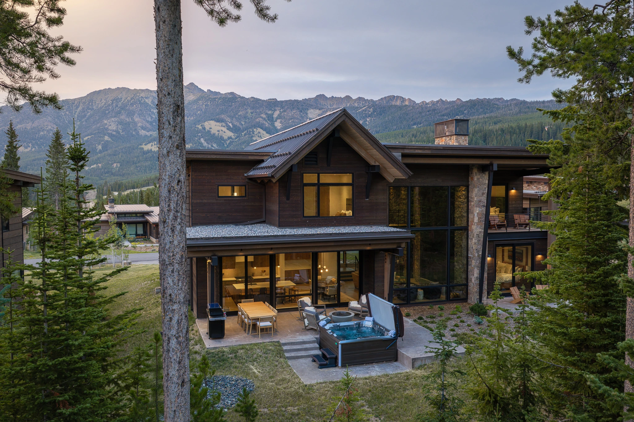 Exterior twilight view with hot tub and mountain backdrop — architectural photography Big Sky Montana, Reid Smith Architects